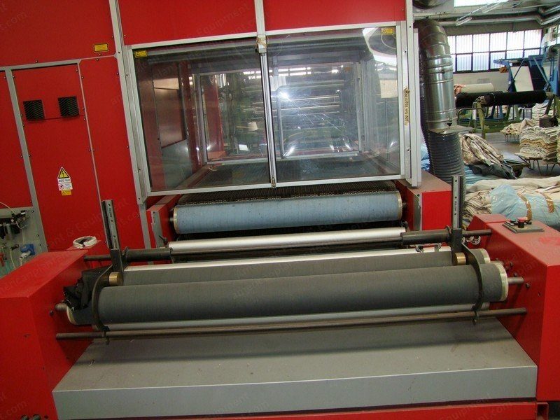 Red laser engraving machine with its safety enclosure open on a converting floor.