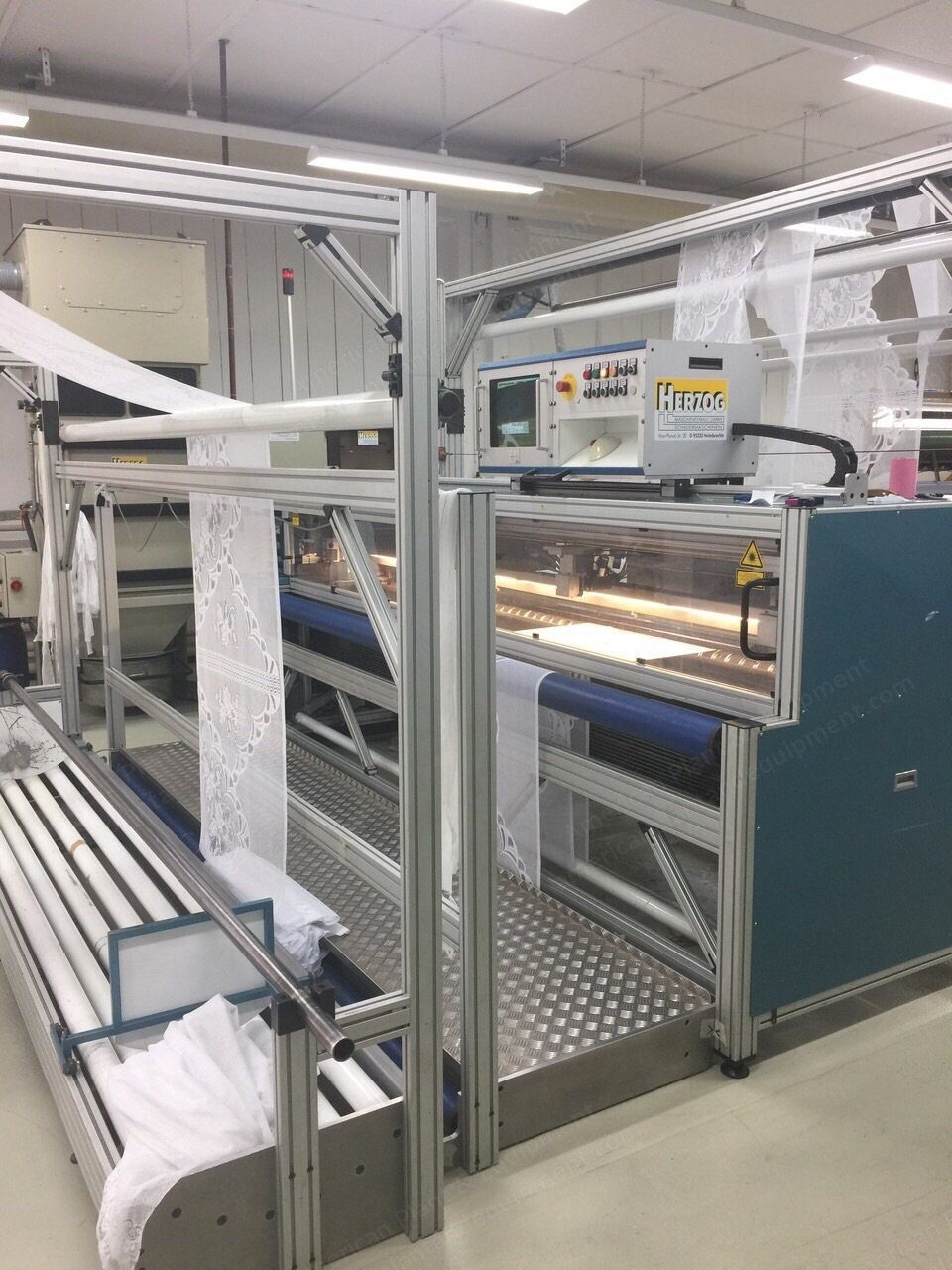Laser cutting machine with twin cutting devices and a fabric feed table.