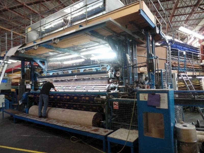 Wide view down a frame Axminster carpet loom with the warp beams and jacquard above.