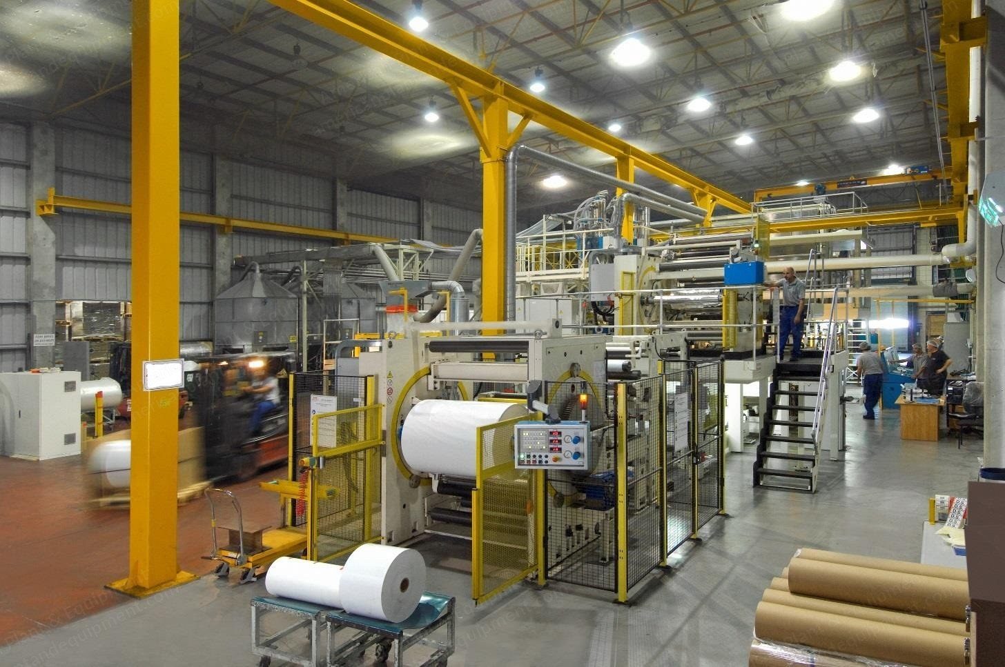 Wide view of an extrusion laminating and coating line running inside a converting plant.